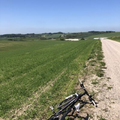 Cykel liggende på jorden mens man ser en grusvej ned langs markerne